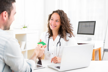 Young attractive doctor taking health insurance card