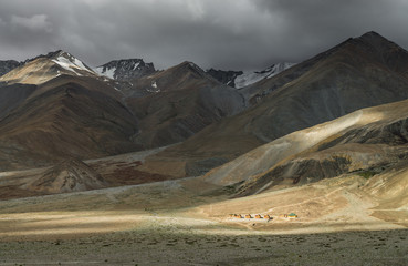 Sun beam drop on small houses in countryside surround by mountain range in summer that show how big nature it is. 