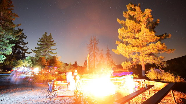 Time lapse footage with tilt up motion of a group of campers surrounding bonfire in alpine mountain in Angels National Forest, California