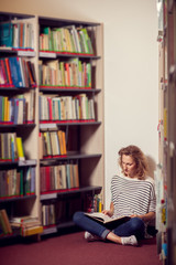 In the library, student girl or young woman with bookssiting bet