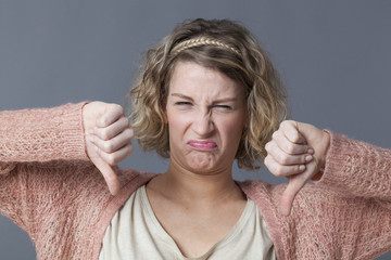 grumpy girl expressing disgust,disagreement and dislike with thumbs down