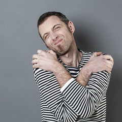 disappointed 40s man crossing his arms on shoulders for expressing regret