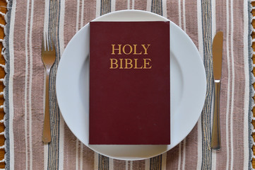 Bible on a dinner plate with silverware in lent