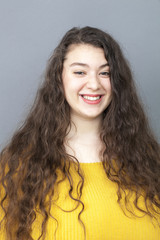 natural smile - smiling xxl woman with long curly brown hair expressing happiness,studio shot