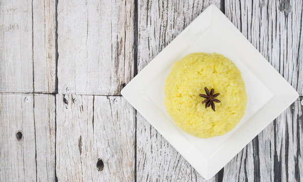Malaysian dish Yellow Glutinous Rice or locally known as Pulut Kuning on white plate over wooden background