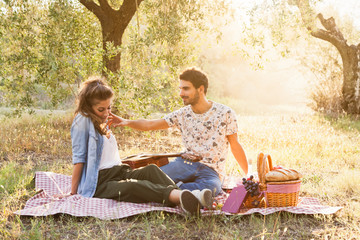 On a beautiful sunny day, a couple of young lovers, makes a picninc on the grass among olive groves...