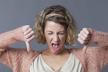 nauseated girl expressing disgust,disagreement and dislike with thumbs down