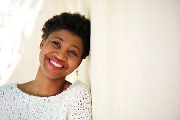 Smiling african american girl leaning against white wall