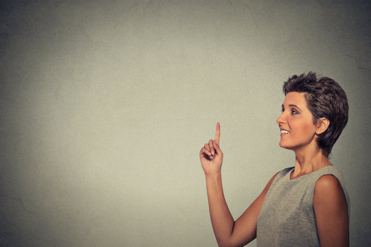 woman pointing at copyspace isolated on gray wall background