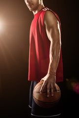 Basketball player holding ball isolated on black background