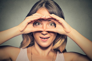 stunned curious woman, peeking looking through fingers like binoculars