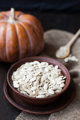Bowl with toasted pumpkin seeds and wooden spoon