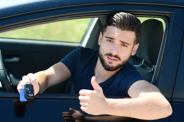 handsome and happy young man in car showing car keys