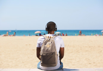 Man sitting by the beach listening to music on headphones
