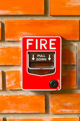Fire Alarm Switch on the orange brick wall background texture.