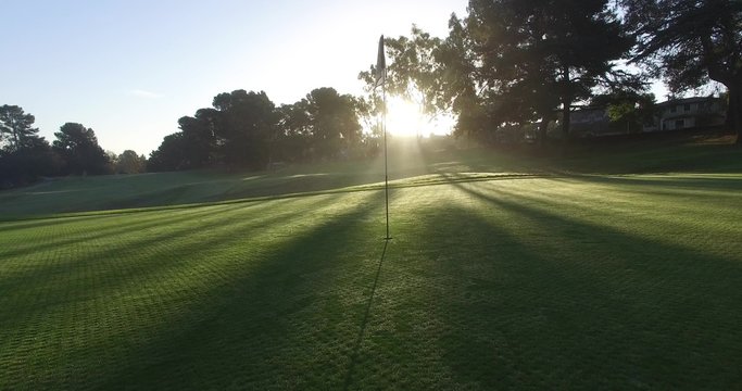 Motion golf course flagstick dramatic beautiful sun rays light shadow gorgeous green early morning 