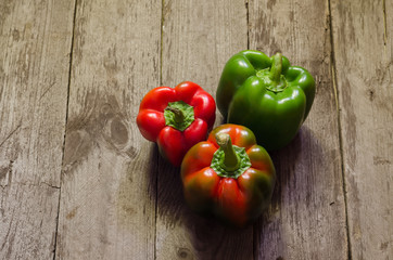 Green and red pepper on wooden background, selective focus