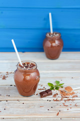 Chocolate and banana smoothie with chocolate balls in jars  on white rustic table 