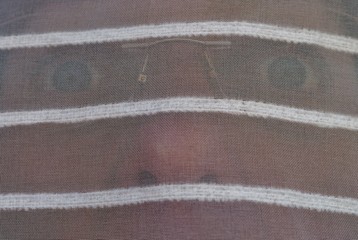 Schreckgeweitete Augen hinterr Gardine