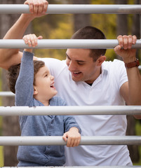 Fototapeta premium Happy father and son having fun in autumn parkHappy father and son having fun in autumn park