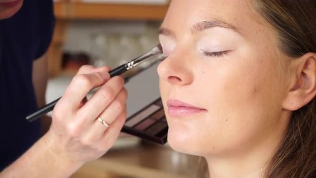 Makeup artist applying with brush eyeshadow on female eye. 4K