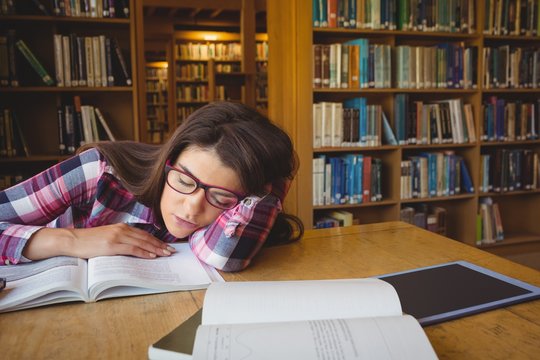 Female student napping on book in library