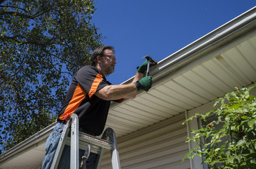Worker Repairing A Gutter On A Customers Home