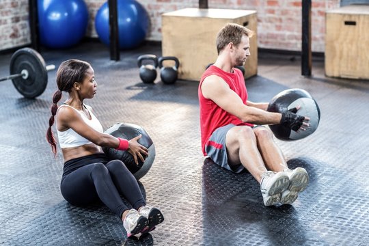 Muscular couple doing ball exercise 
