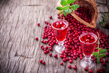 Sweet cranberry liqueur in two glasses on the background of ripe berries