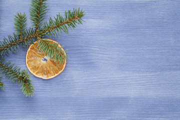 Fototapeta na wymiar spruce twig with dried orange slices on blue table, christmas