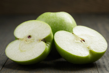 ripe green apples sliced on wood table