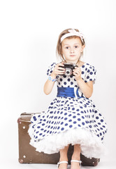 Little girl sitting on an old suitcase