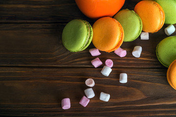 Scattered french macaroons and marshmellow in dark wooden background