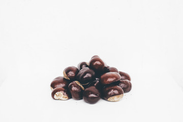 Pile of glossy horse chestnut seeds on white background retro-styled 