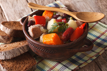 Eintopf rich soup with meat, sausages and vegetables close-up 
