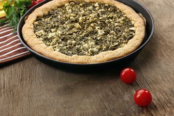 Open pie with spinach and tomato cherry on table close up