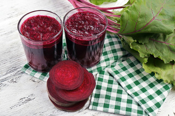 Glasses of beet juice with vegetables on table close up