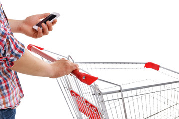 Young man holding mobile phone and shopping cart isolated on white