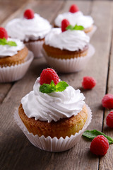 Delicious cupcakes with berries and fresh mint on wooden table close up