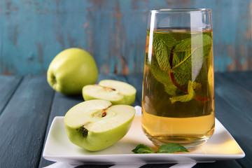 Glass of apple juice with fruits and fresh mint on table close up