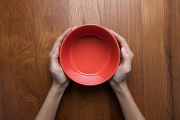 A female hands hold a empty(blank) white dish(plate) on the wood