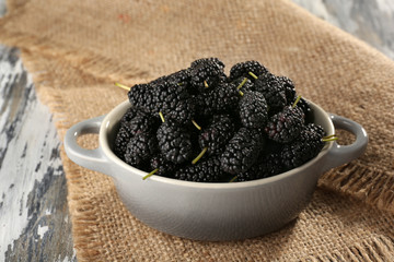 Ripe mulberries in bowl on table close up