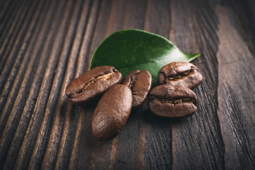 Coffee beans with leaf on wooden background