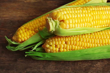 Fresh corn on cobs on wooden table, closeup