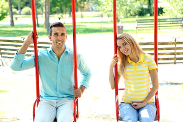 Obraz premium Young pregnant woman with husband on swing outdoors