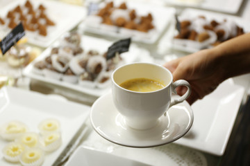 Female hand holding cup of coffee on table background