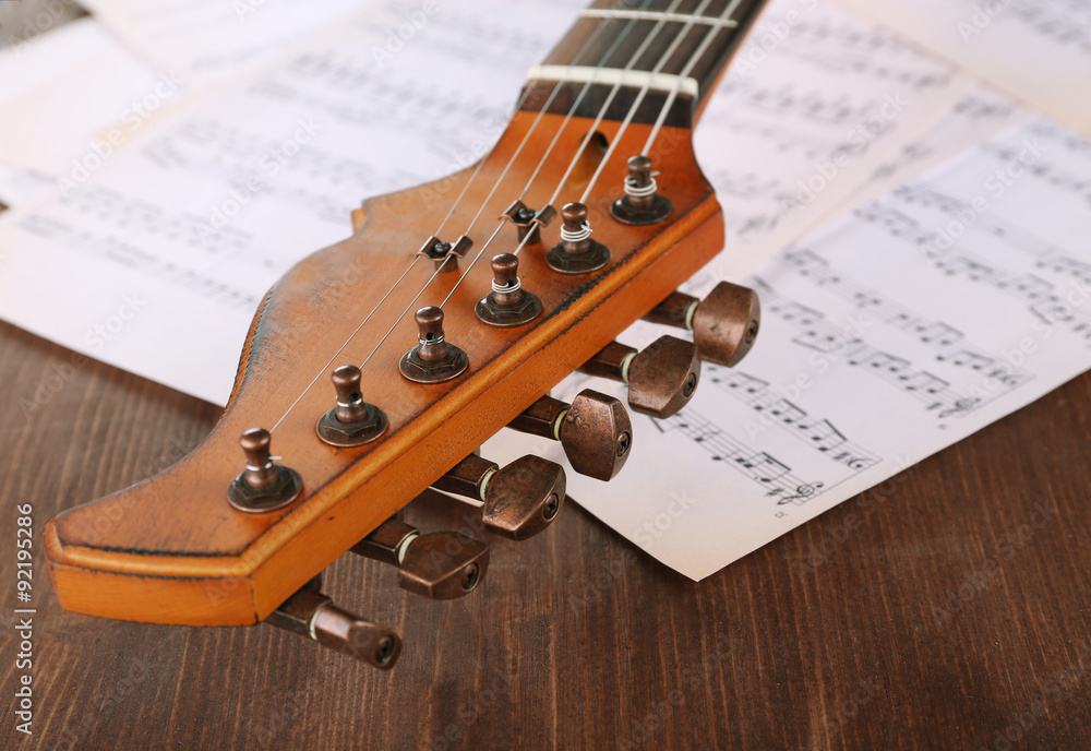 Wall mural electric guitar with music notes on wooden table close up