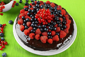 Delicious chocolate cake with summer berries on green tablecloth, closeup
