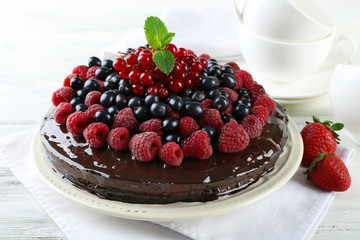 Delicious chocolate cake with summer berries on wooden table, closeup