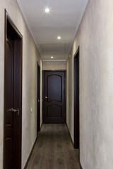 narrow corridor with four brown doors